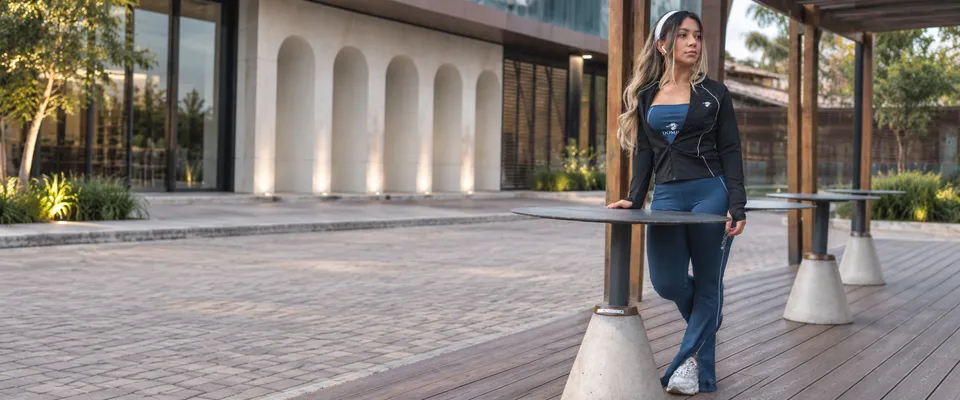 Mulher usando conjunto Dominus azul-marinho com jaqueta preta em pátio moderno